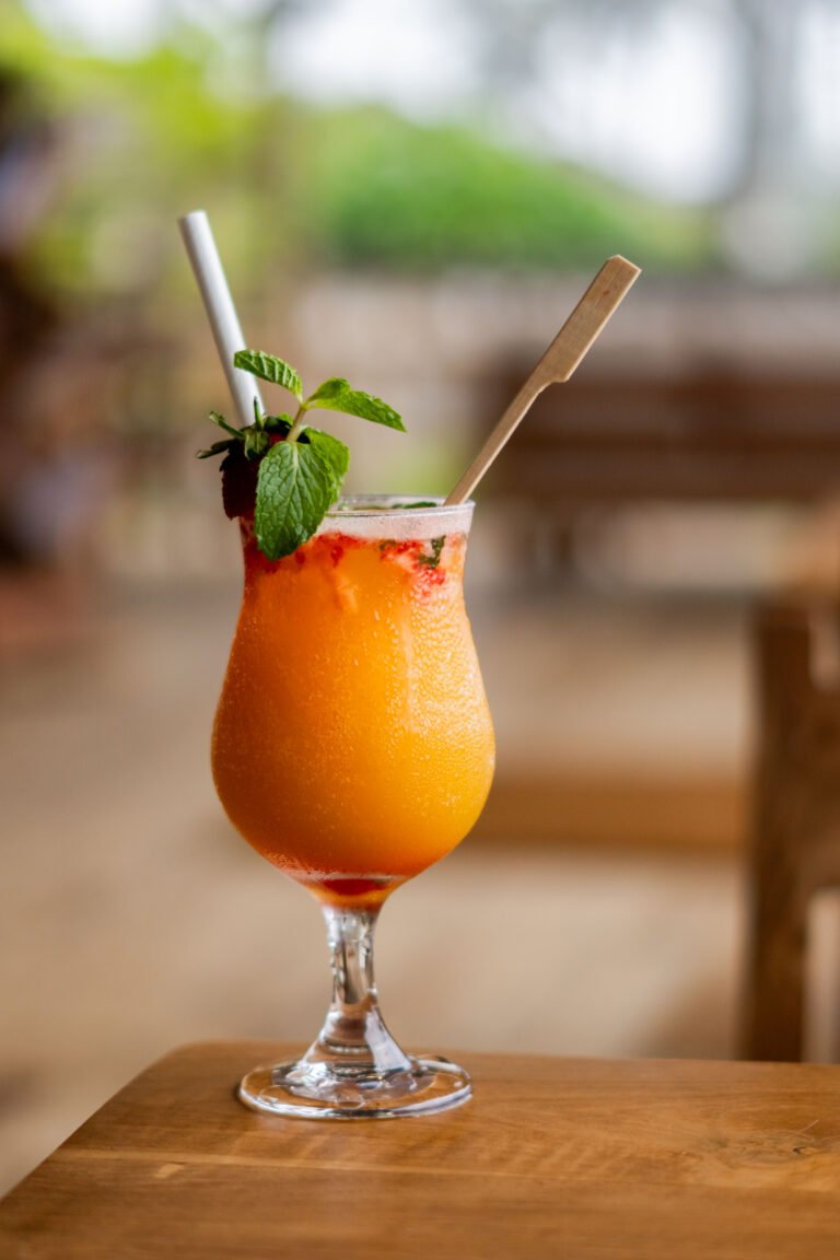 Orange tropical cocktail with garnish on a wooden table at Coco Kitchen