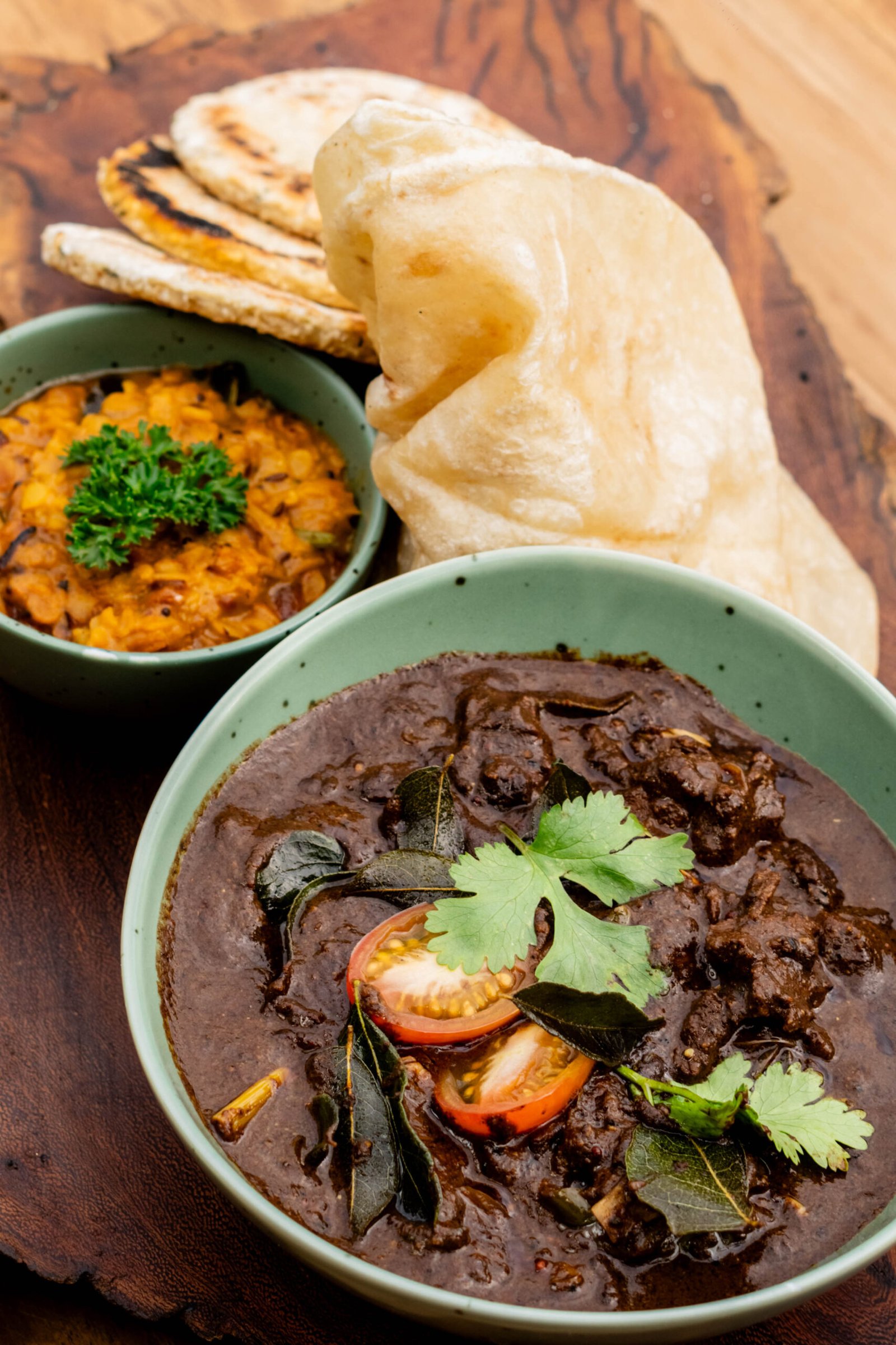 Sri Lankan curry, dhal, roti and papadums served on a wooden board